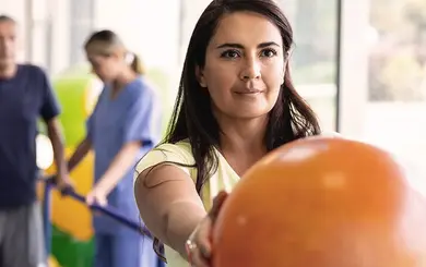 Frau mit ausgestreckten Armen hält einen Ball