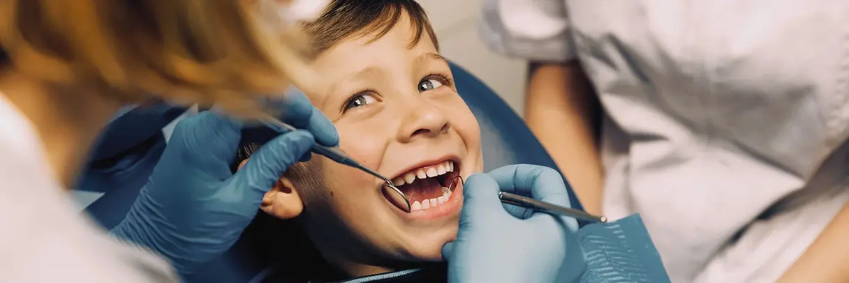 Zahnärztin schaut in den Mund eines lächelnden Jungen