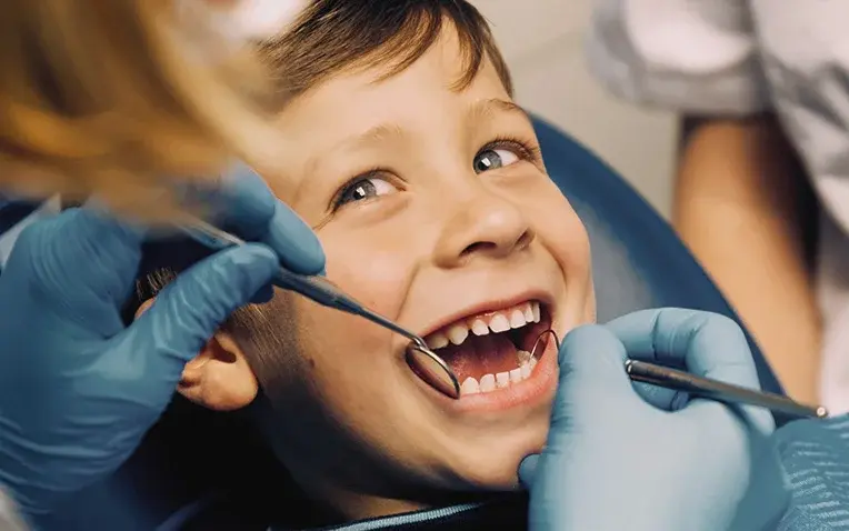 Zahnärztin schaut in den Mund eines lächelnden Jungen