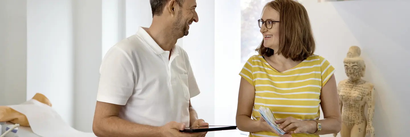 Arzt und Patientin im Gespräch, Arzt hält ein Tablet in der Hand (Symbolbild)