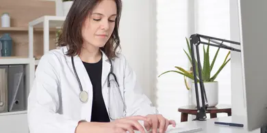 Ärztin tippt eine Nachricht am Computer