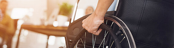 Hand und Rad eines Rollstuhlfahrers