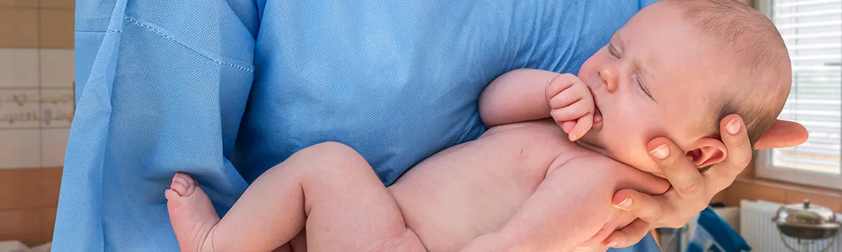 Hebamme hält neugeborenes Baby im Arm
