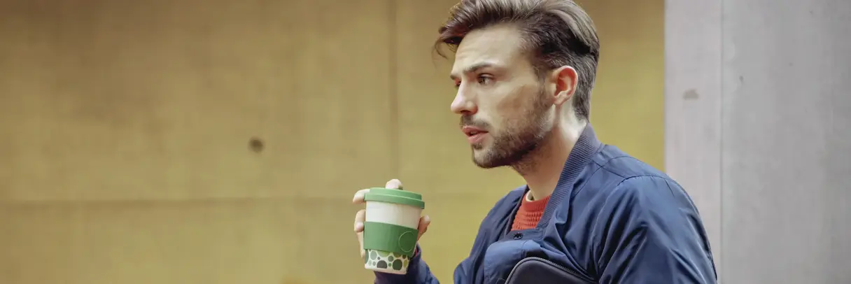 Junger Mann mit Kaffeebecher und Smartphone Das Bild zeigt einen jungen Mann mit Kaffeebecher und Smartphone.