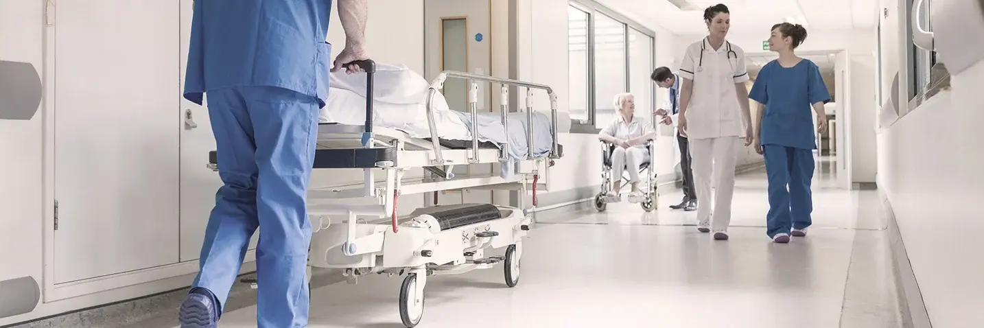 Mehrere Personen laufen durch Flur eines Krankenhauses