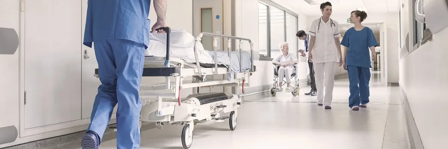 Klinikbetrieb allgemein Mehrere Personen laufen durch Flur eines Krankenhauses