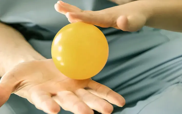 Ergotherapeut und Kind, haben in einer Hand mit einem kleinen Ball und machen Übung