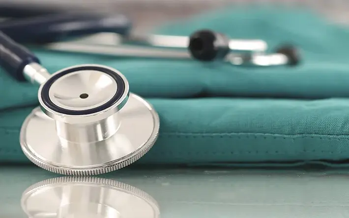 Arztkleidung und Stethoskop liegen auf Tisch