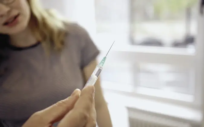 Vor einer Impfung: Patientin betrachtet Spritze (Symboldbild)