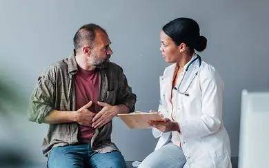 Zu sehen ist eine Hausärztin im Gespräch mit einem Patienten.