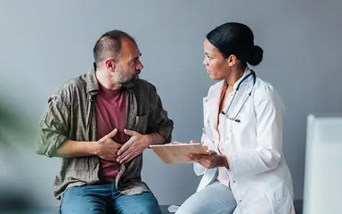 Zu sehen ist eine Hausärztin im Gespräch mit einem Patienten.