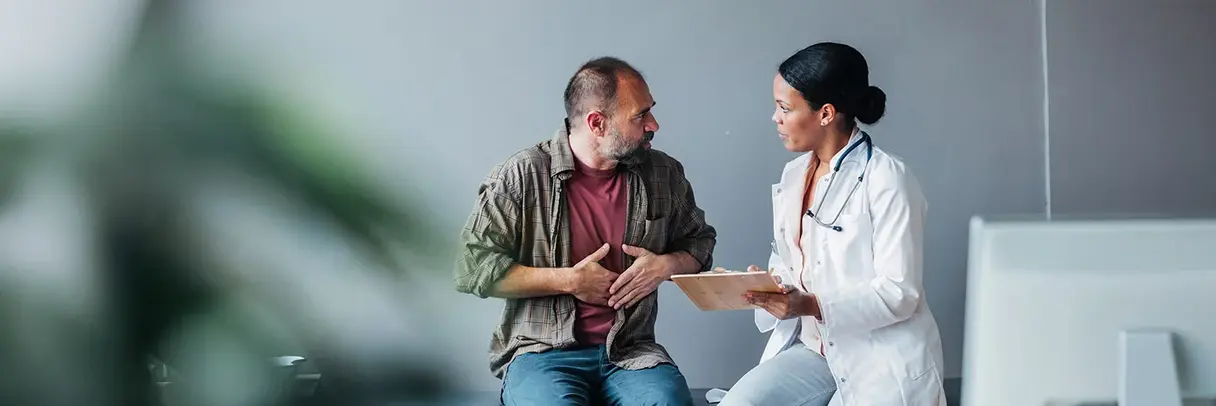 Hausärztin im Gespräch mit einem Patienten Zu sehen ist eine Hausärztin im Gespräch mit einem Patienten.