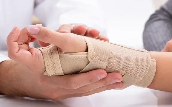 Arzt hält bandagiertes Handgelenk