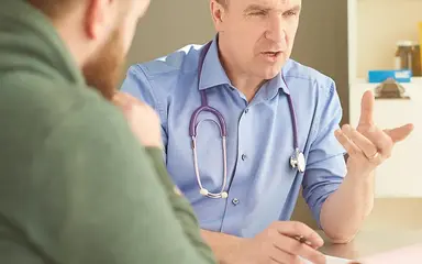 Das Bild zeigt einen Arzt im Gespräch mit einem Patienten. Der Arzt verschreibt dem Patienten ein E-Rezept.