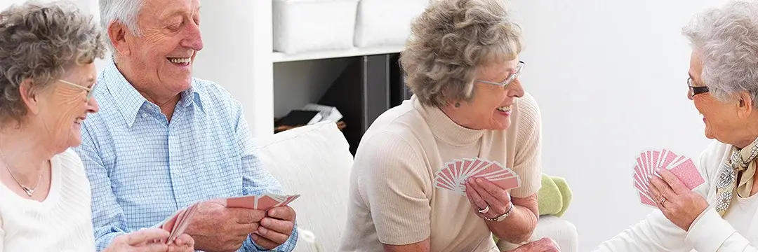 Gruppe von glücklichen älteren Männern und Frauen beim Kartenspiel 
