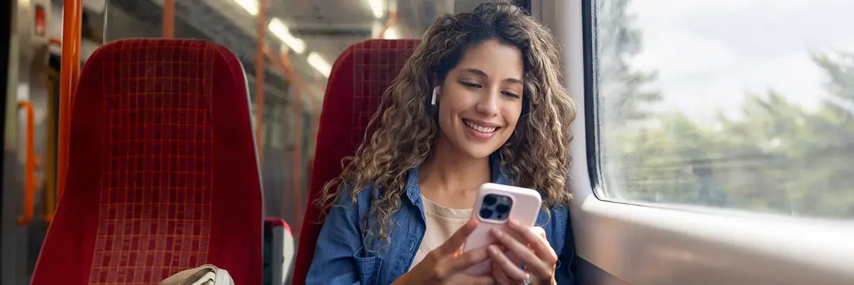 Junge Frau hört Podcast Das Bild zeigt eine junge Frau, die bei der Fahrt in einem Zug einen Podcast über ihr Smartphone hört.