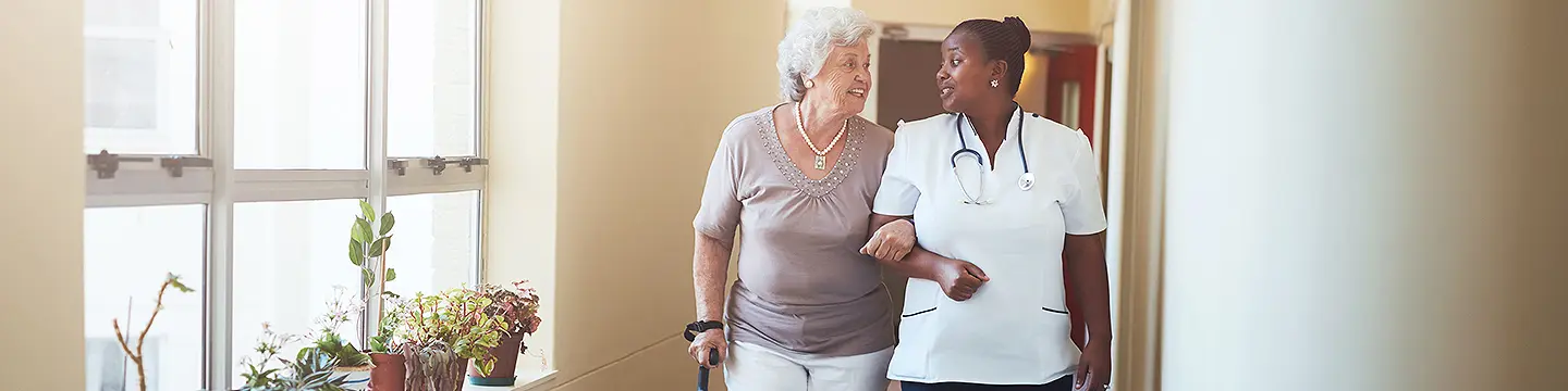 Pflegerin hilft älterer Dame beim Gehen