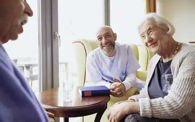 Altenpfleger spricht mit älterer Dame. Symbolbild für Pflege im Pflegeheim.