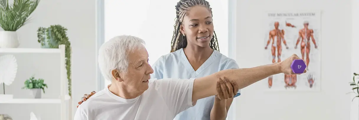 Physiotherapie Schulter Das Bild zeigt eine Physiotherapeutin, die einen älteren Mann mit Schulterbeschwerden behandelt.