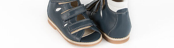 Ein Paar dunkelblauer orthopädischer Kindersandalen auf weißem Grund