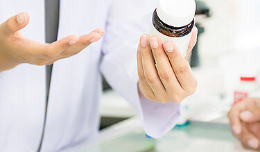 Hände von Apothekerin mit Medikamenten-Flasche (Symboldbild)