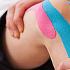 Therapeut macht Übungen mit getapten Knie 