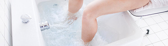 Beine eines jungen Mannes stehen in einem Becken mit sprudelndem Wasser
