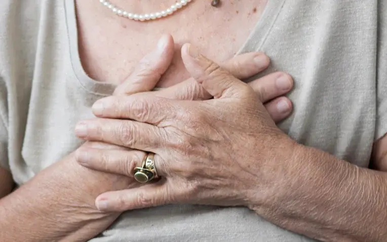 Das Bild zeigt eine Frau, die ihre Hände auf ihr Herz hält. Es handelt sich um ein Symbolbild für Herzinsuffizienz.