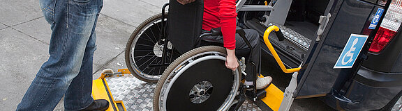 Mann hilft Rollstuhlfahrer in Transportwagen