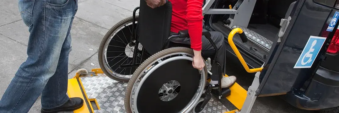 Mann hilft Rollstuhlfahrer in Transportwagen