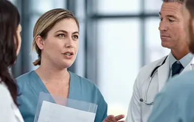 Zusammenarbeit unter medizinischem Fachpersonal: Das Bild zeigt Pflegekräfte, Ärztinnen und Ärzte im Gespräch.