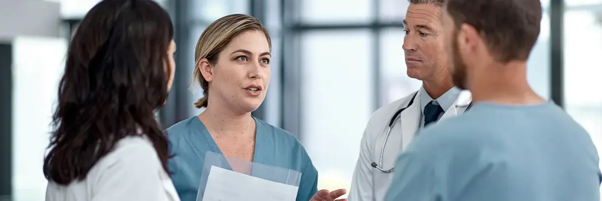 Zusammenarbeit unter medizinischem Fachpersonal: Das Bild zeigt Pflegekräfte, Ärztinnen und Ärzte im Gespräch.