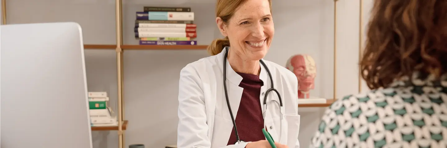 Das Bild zeigt eine Ärztin im Gespräch mit einer Patientin. Die Ärztin lächelt.