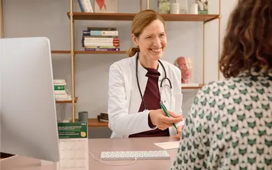 Das Bild zeigt eine Ärztin im Gespräch mit einer Patientin. Die Ärztin lächelt.