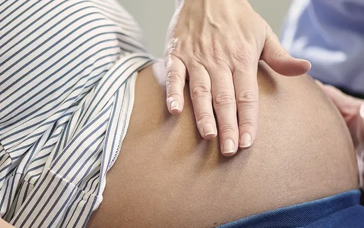 Foto: Hebamme tastet den Bauch einer Schwangeren ab