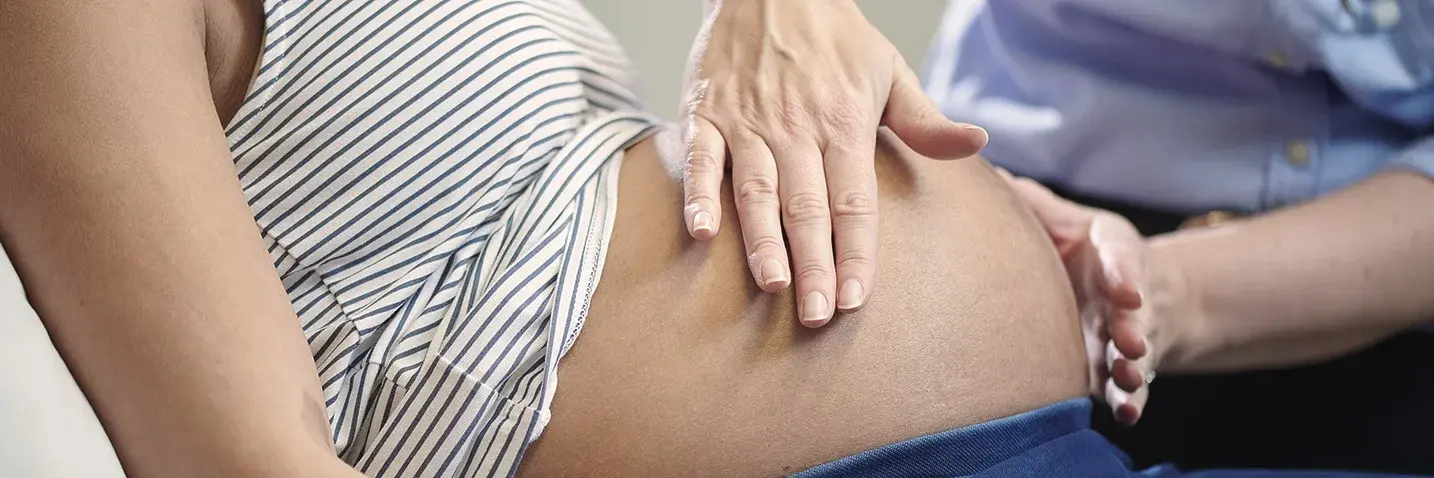 Hebamme Hebamme tastet Bauch einer schwangeren Frau ab