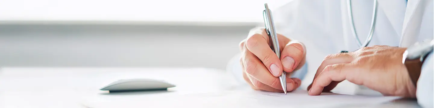 Arzt hält einen Stift in der Hand und schreibt eine Verordung oder Rezept
