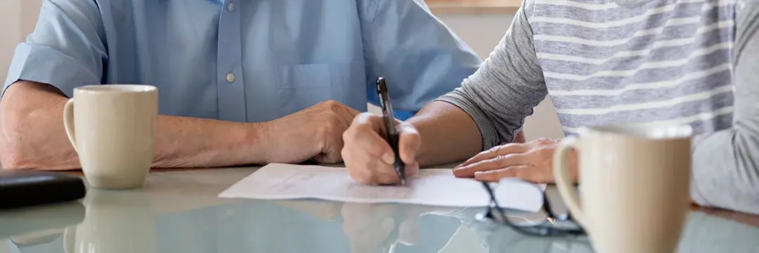 Weibliche Pflegekraft hilf älteren Mann beim Ausfüllen von Dokumenten