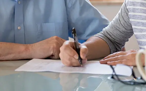 Weibliche Pflegekraft hilf älteren Mann beim Ausfüllen von Dokumenten