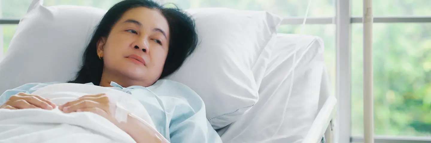 Frau nach Operation im Krankenhausbett Das Bild zeigt eine Frau mittleren Alters, die nach einer Operation in einem Krankenhausbett liegt.
