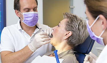 Zahnuntersuchung: Zahnarzt kontrolliert die Zähne einer Patientin