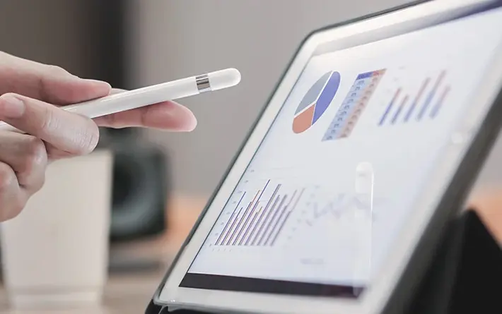 Hand zeigt mit einem Stift auf ein digitales Chart