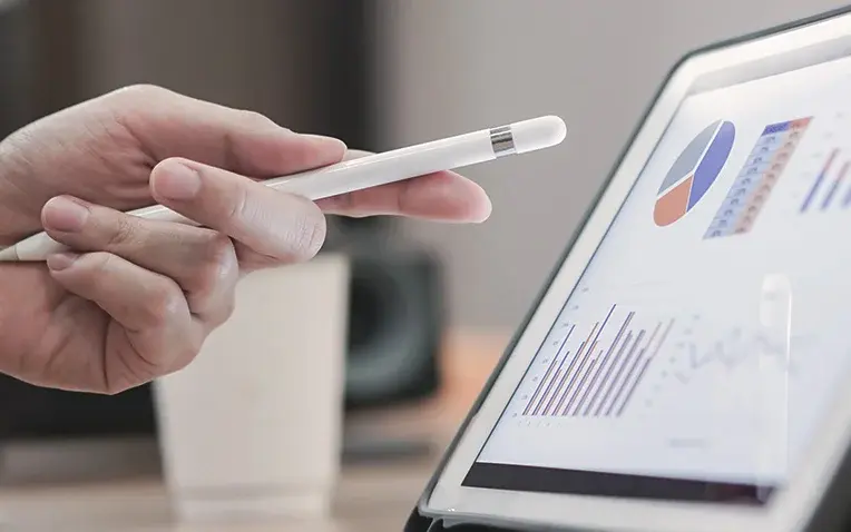 Foto: Hand einer Person zeigt auf ein Chart im Tablet.