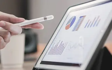 Hand zeigt mit einem Stift auf ein digitales Chart
