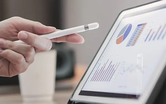 Person zeigt mit Stift in der Hand auf ein Tablet