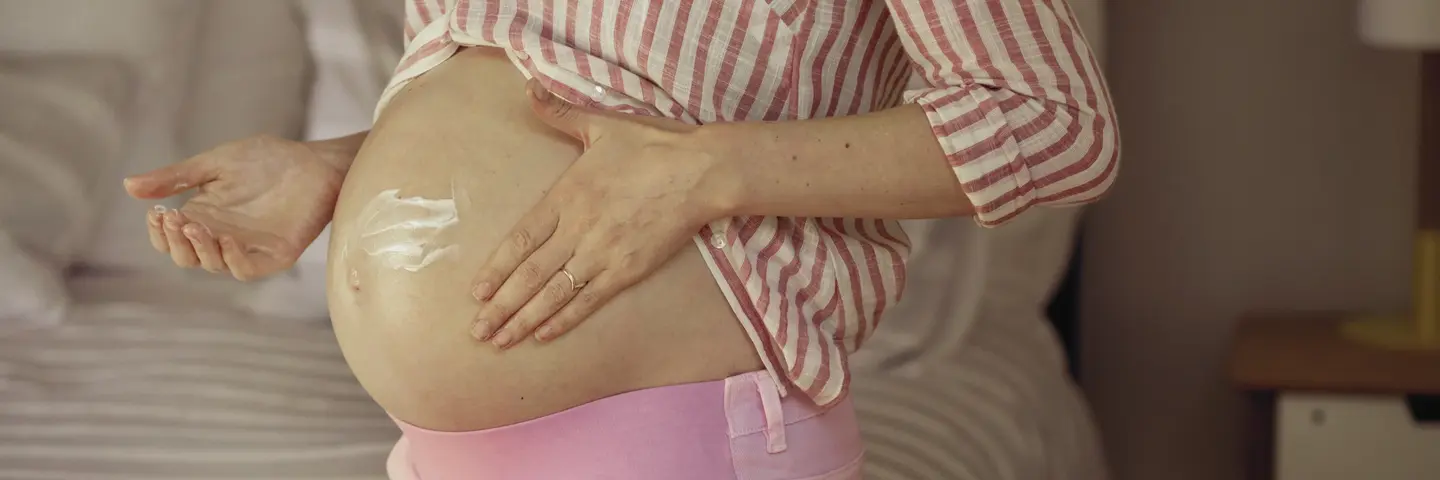 Eine schwangere Frau cremt ihren Bauch ein. Eine schwangere Frau cremt ihren Bauch ein.