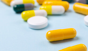 Tabletten und Kapseln auf blauem Hintergrund (Symbolbild)