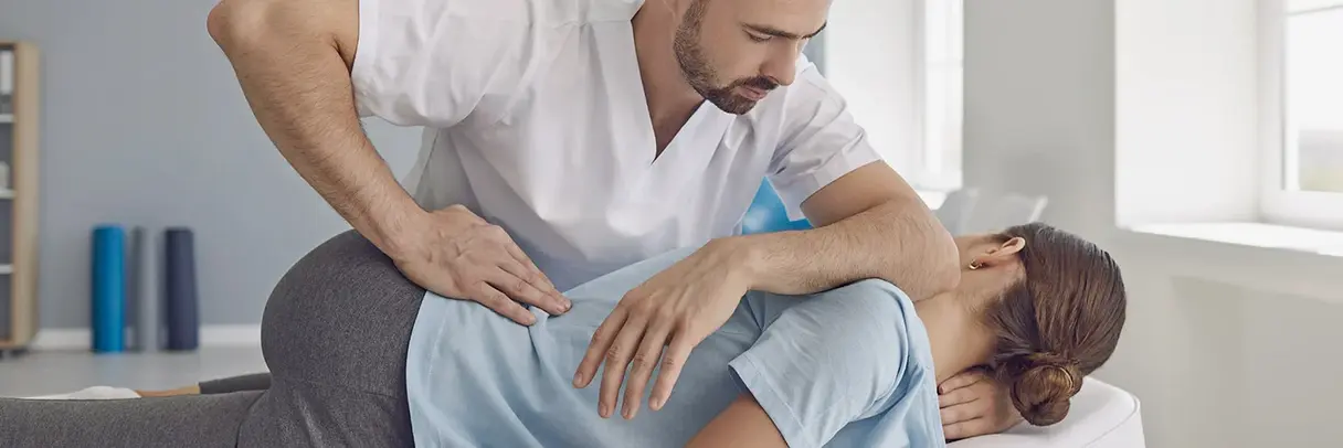 Physiotherapie bei Rückenschmerzen Das Bild zeigt einen Physiotherapeuten, der eine Patientin mit Rückenschmerzen behandelt.