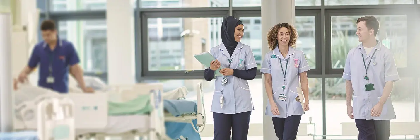 Junge Pflegerinnen und Pfleger laufen durch ein Krankenhaus