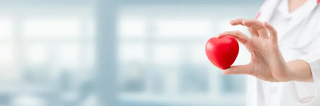 Eine Frau hält ein rotes kleines Spielzeugherz in die Kamera.